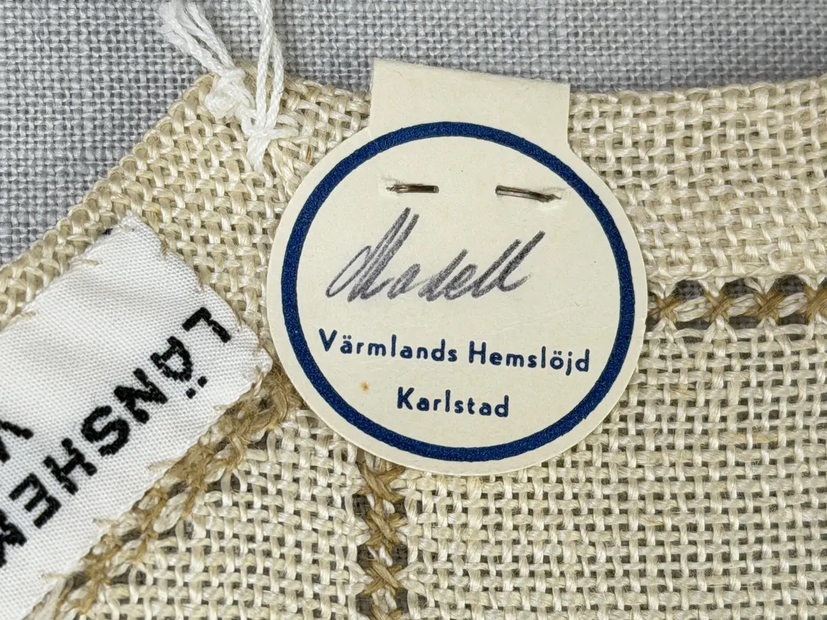 Åttkantig duk gjord av linneväv med 10tr/cm i tuskaft och broderi utfört med lingarn i sex olika bottensömmar. Dukens kanter har en 16mm bred dubbelvikt fåll runt om fastsydd med kaststygn samt en myrgångs- söm.