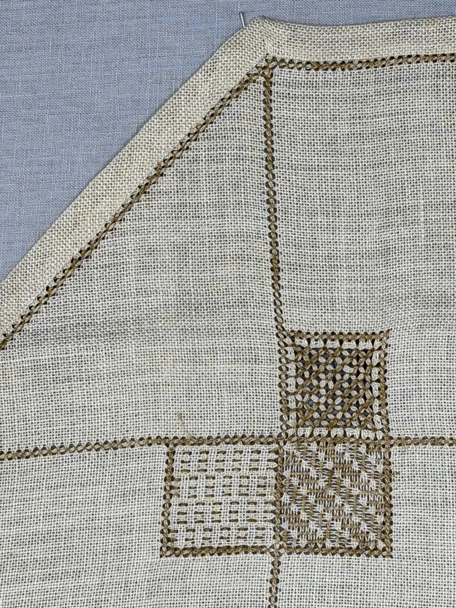 Åttkantig duk gjord av linneväv med 10tr/cm i tuskaft och broderi utfört med lingarn i sex olika bottensömmar. Dukens kanter har en 16mm bred dubbelvikt fåll runt om fastsydd med kaststygn samt en myrgångs- söm.