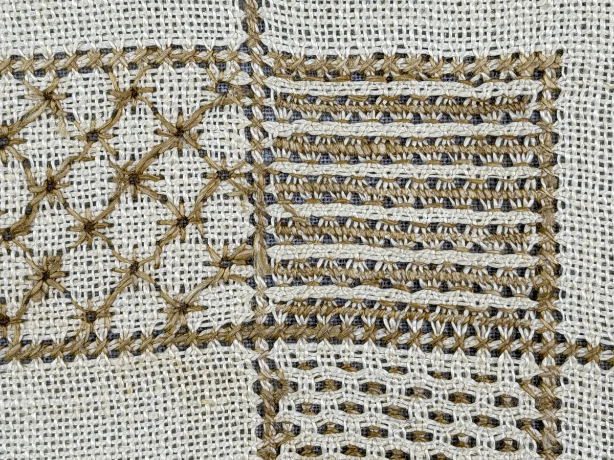 Åttkantig duk gjord av linneväv med 10tr/cm i tuskaft och broderi utfört med lingarn i sex olika bottensömmar. Dukens kanter har en 16mm bred dubbelvikt fåll runt om fastsydd med kaststygn samt en myrgångs- söm.