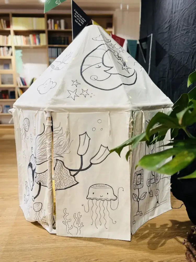 Eit kvitt telt med mange illustrasjonar ståande inne i eit bibliotek