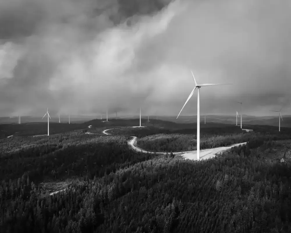 Vindkraftverk i naturmiljö, dramatisk himmel. Svartvitt fotografi.