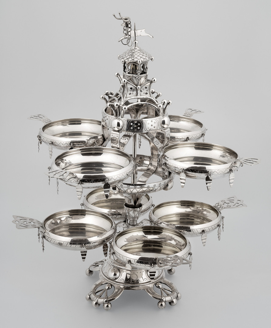 I sentrum av et tilnærmet kjegleformet sokkelparti som hviler på fire lave ben står det en midtsøyle. Til et lite, om søylen dreibart, understativ er det festet 4 sirkulære skåler med gjennombrutt håndtak og åtte nedhengende sølvstykker langs siden. Fire skåler av samme slag bæres av stort dreibart overstativ bestående av to vannrette ringer festet over hverandre med buede vertikale stykker. Stativets bekroning er utformet som et tårn med bjelle og en løpende bukk.