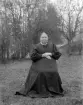 Friluftsporträtt av Karolina Hansdotter, hemmansägarhustru i Viggesbo i Rumskulla. Född och uppvuxen i Svinhult var hon från 1865 gift med bonden August Alexandersson. En längre tid hade paret varit lantbrukare i Gnöst. Från 1879 ägare till Viggesbo. Foto omkring 1903.