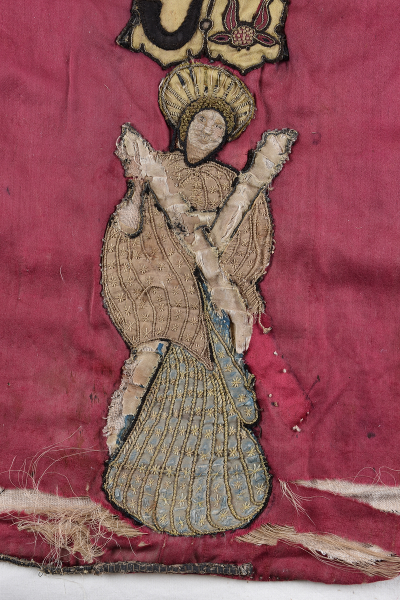 På mässhakens framsida finns en korsformad besättning av vävda guldband. Ryggsidan har även den en korsformad besättning, vilken föreställer Kristus på korset. På korsarmarna finns evangelisternas sinnesbilder. I nedre kanten av korset finns två förenade vapen och därunder en helgonbild. 

Enligt liggare:
"Messhake av rött siden med broderier från 1500-talet; Kristus på korset; på korsarmarna evangelisternas sinnebilder; under korset tvänne förenade vapen, därunder en helgonbild med Andreaskorset"


Neg.nr: 1984-04