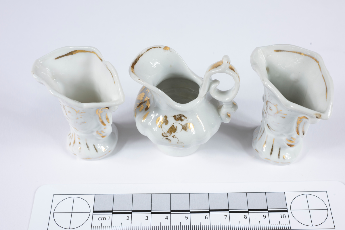 Ofärgad glasyr med obränd gulddekor.
:1 Kaffekanna med lock, H 65 mm.
:2 Sockerskål med lock, H 60 mm.
:3 Gräddkanna, H 55 mm.
:4 Korg, H 60 mm.
:5 Kaffekopp med fat, H 25 mm.
:6 Fat (med druvklase i relief) Diam 60 mm.
:7 Vas, H 60 mm.
:8 Vas, H 60 mm.