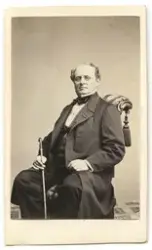 Porträtt på en man i helfigur, sittande.