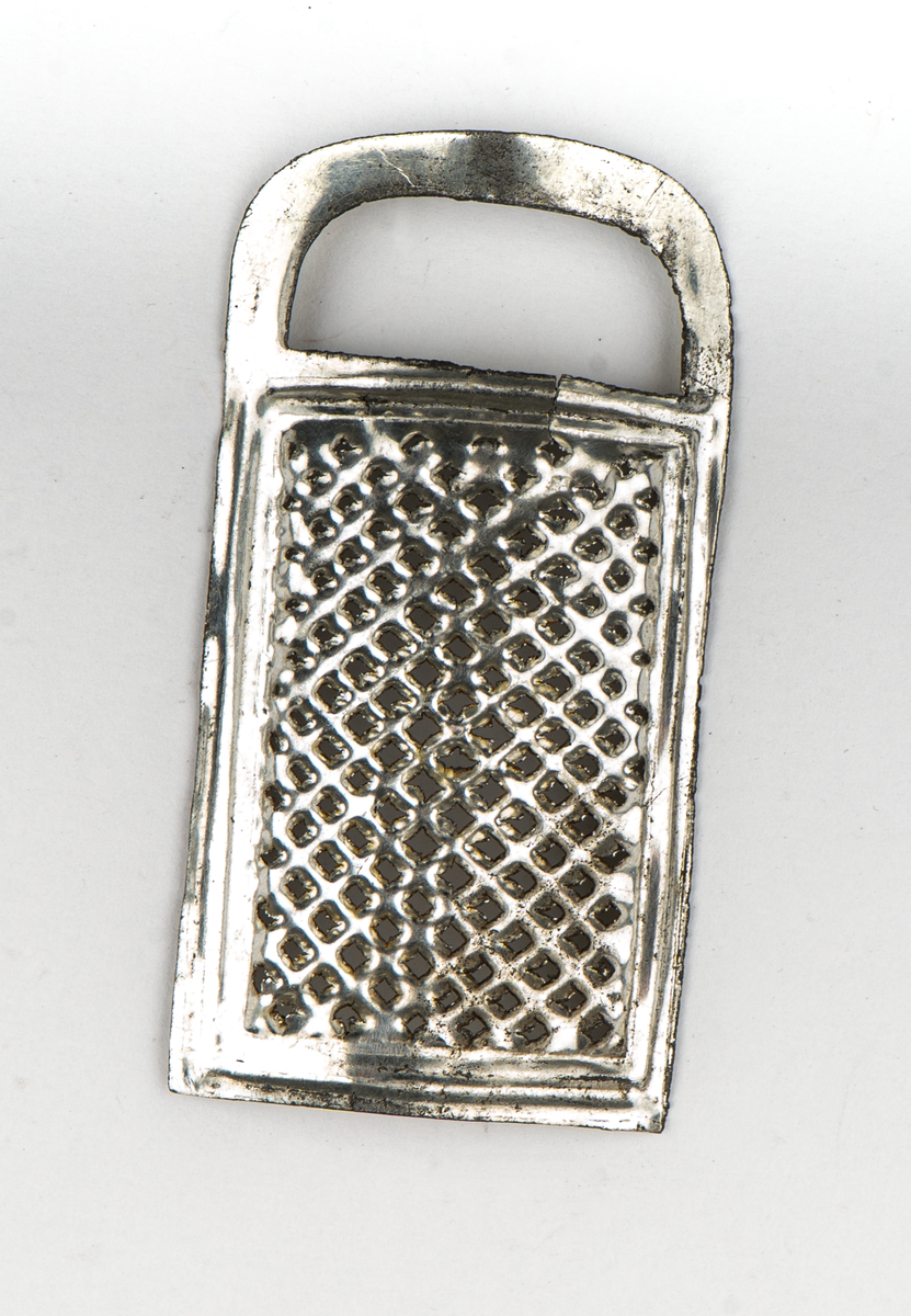 Rivjärn, 1-3, av vitmetall. En rektangulär skiva välvd.
Ytan fylld av rivtaggar. upptill ett format handtag.
1 och 2 är större än 3.

Tillhör leksakssamling GM17037a-k.