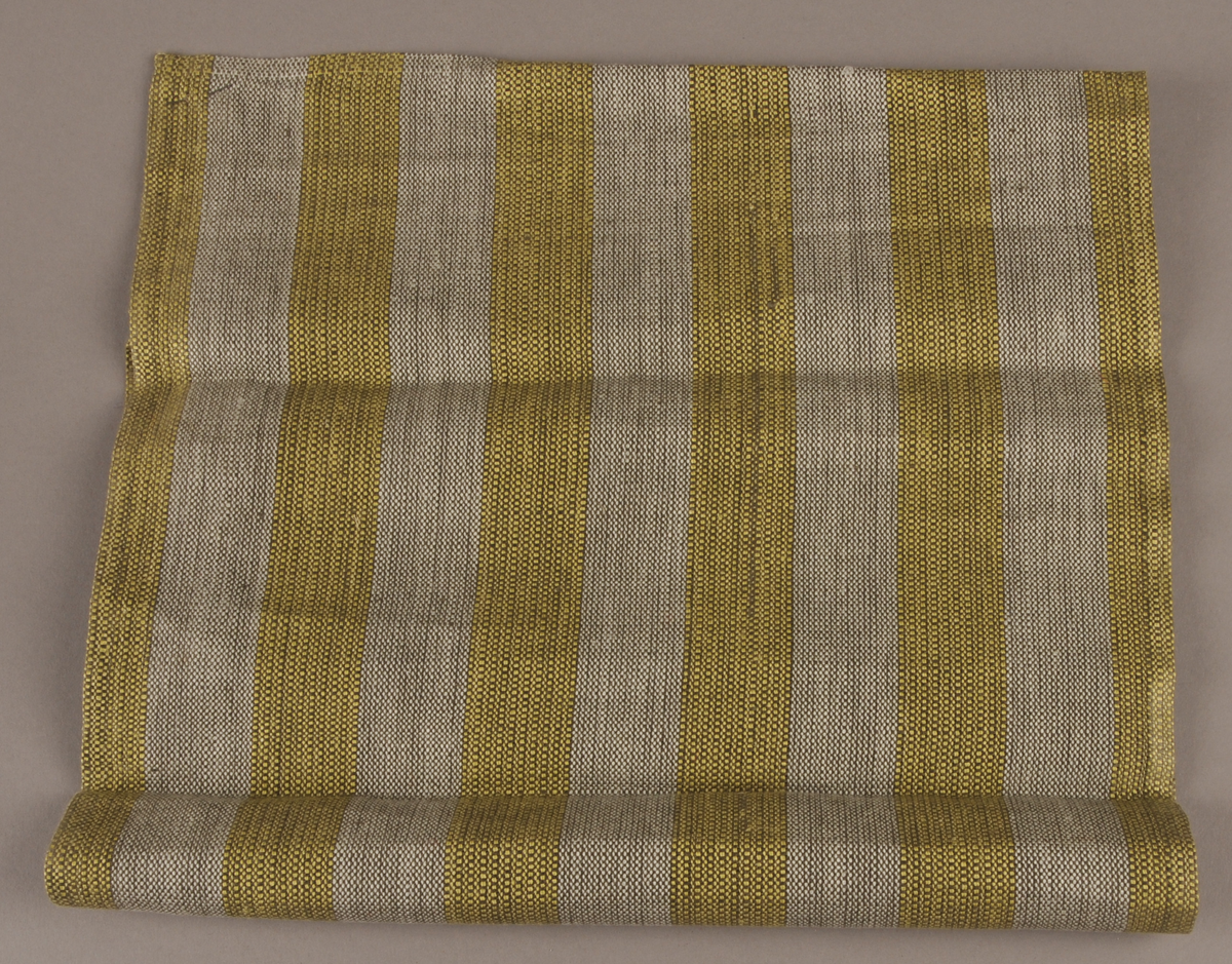 Voven stoffbit med stripemønster. Falda inn på alle sidene. Merkelapp med teksten "nr 20 ca 7,50 pr. brikke.