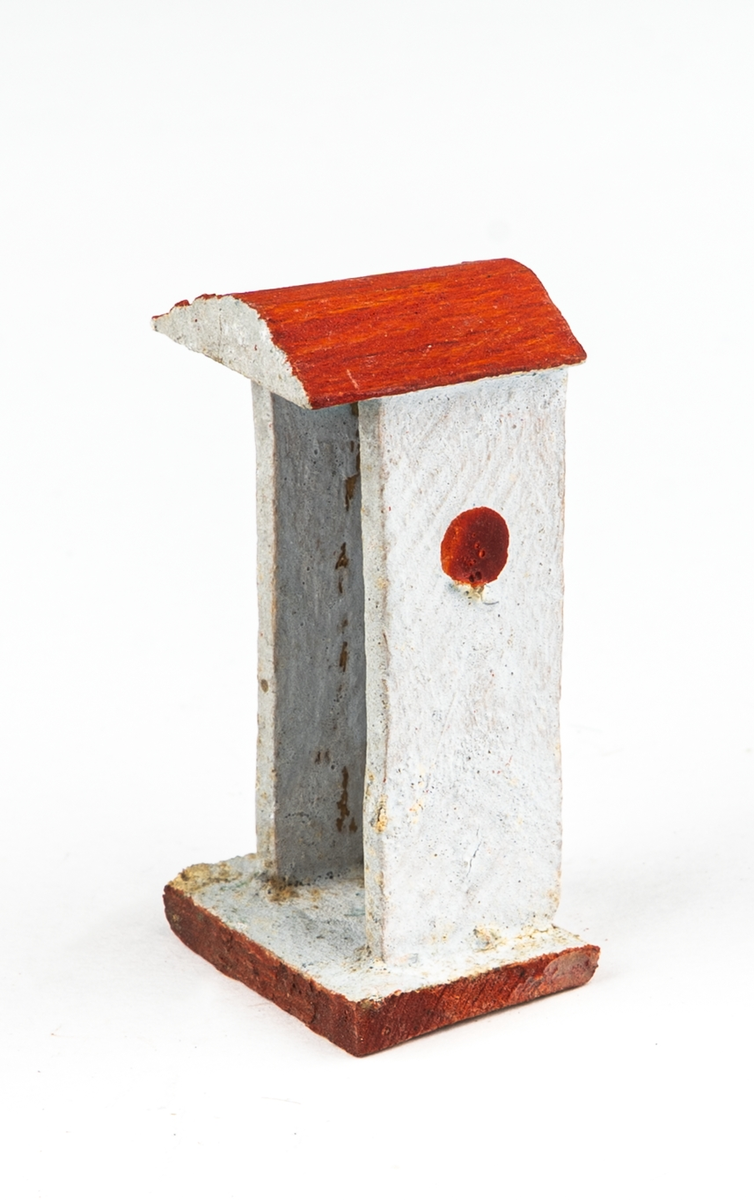 Vaktkur av trä med lös soldat. Fyra kurar, 20 soldater. Kuren ljusgrå med rödbrunt sadeltak och fotplatta med brun kant. På sidorna rund röd fläck markerande fönsterglugg. Soldaten i grå uniform med vita knappar, "rundkullig" hjälm och bruna stövlar. Gevär. Kurar och soldater skiljer sig något i utförandet. 2 soldater har tappat geväret, en saknar fotplatta.