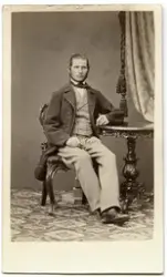 Porträtt på en man i helfigur, sittande.