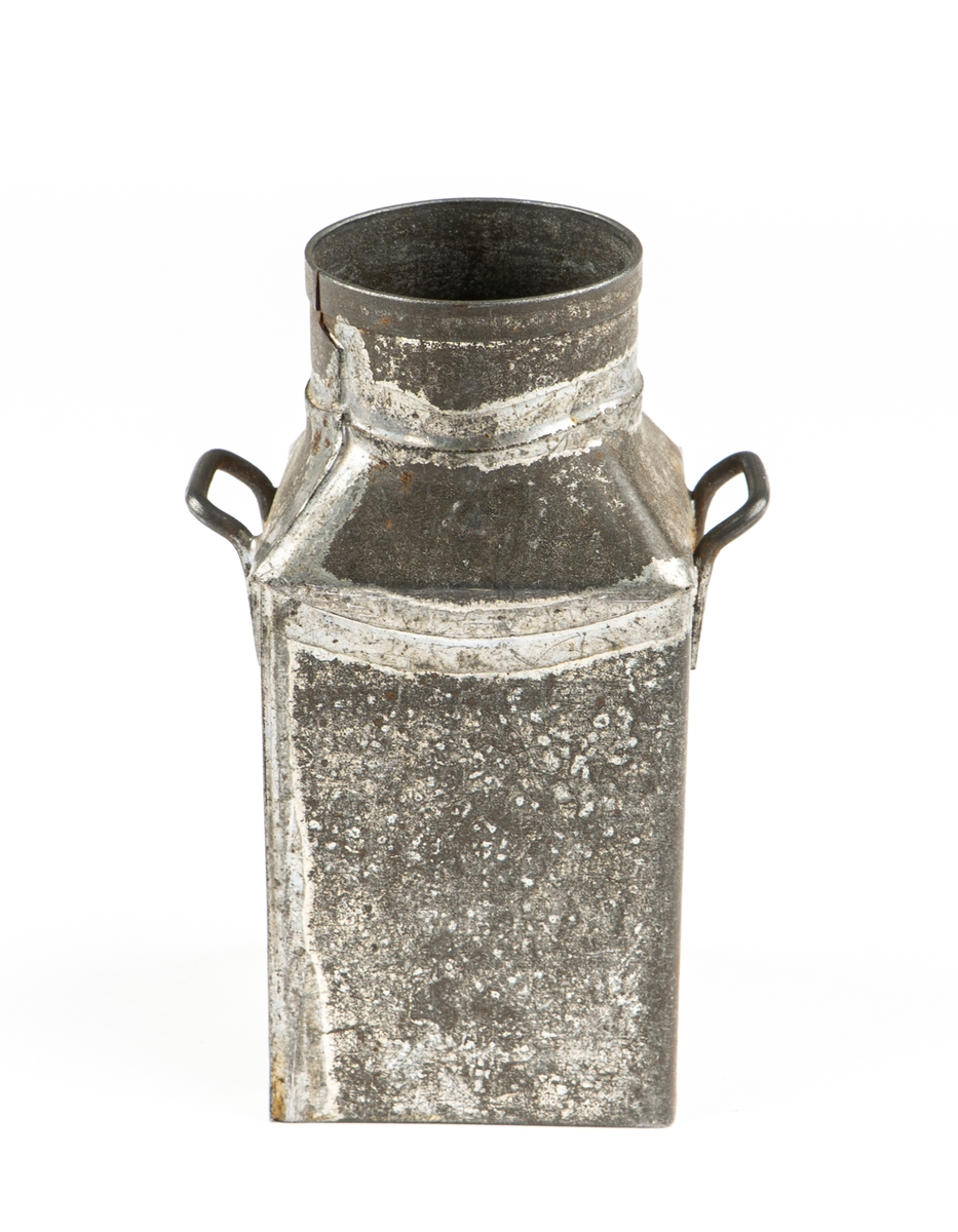 Leksak. Mjölkflaskor, 4 st identiska.
Fyrsidiga med insvängda, raka, partier överst och
hög cylindrisk krage. Bärhänklar på motstående sidor.
Lock saknas på tre  (?).
Ett löst lock med träpackning och lyftögla finns.
Ev. hithörande?. Delarna hoplödda.