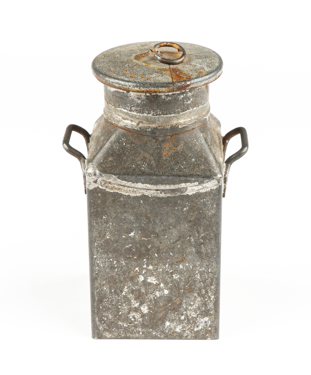 Leksak. Mjölkflaskor, 4 st identiska.
Fyrsidiga med insvängda, raka, partier överst och
hög cylindrisk krage. Bärhänklar på motstående sidor.
Lock saknas på tre  (?).
Ett löst lock med träpackning och lyftögla finns.
Ev. hithörande?. Delarna hoplödda.