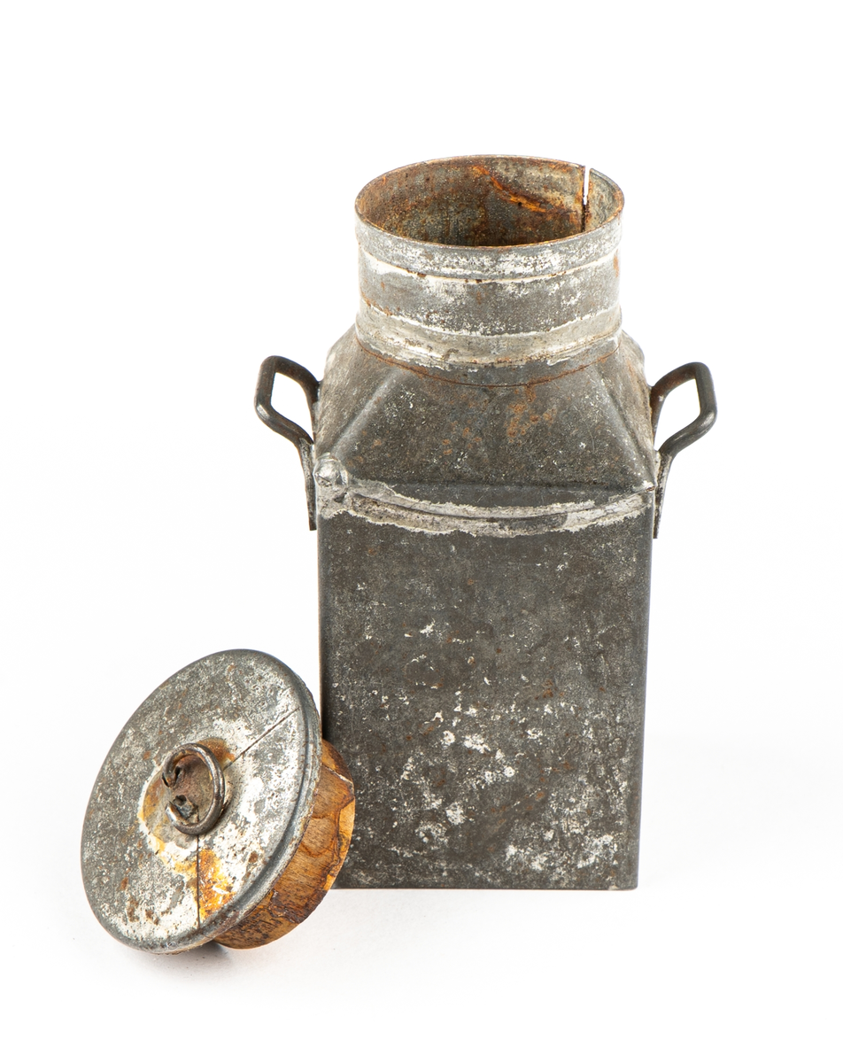 Leksak. Mjölkflaskor, 4 st identiska.
Fyrsidiga med insvängda, raka, partier överst och
hög cylindrisk krage. Bärhänklar på motstående sidor.
Lock saknas på tre  (?).
Ett löst lock med träpackning och lyftögla finns.
Ev. hithörande?. Delarna hoplödda.