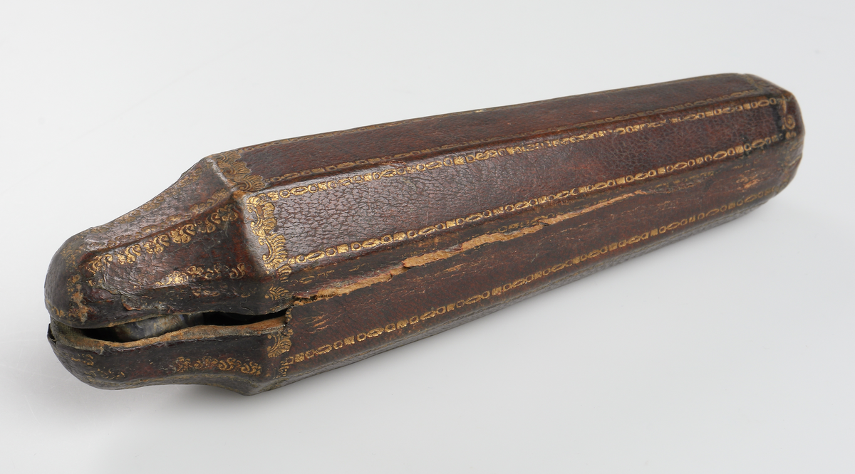 Parfymflaska av slipat glas med silverkork. Förvaras i ett brunt etui av läder med gulddekor. Etuiet stängs med två små mäsingshaspar. 

Inskrivet i huvudbok år 1963.