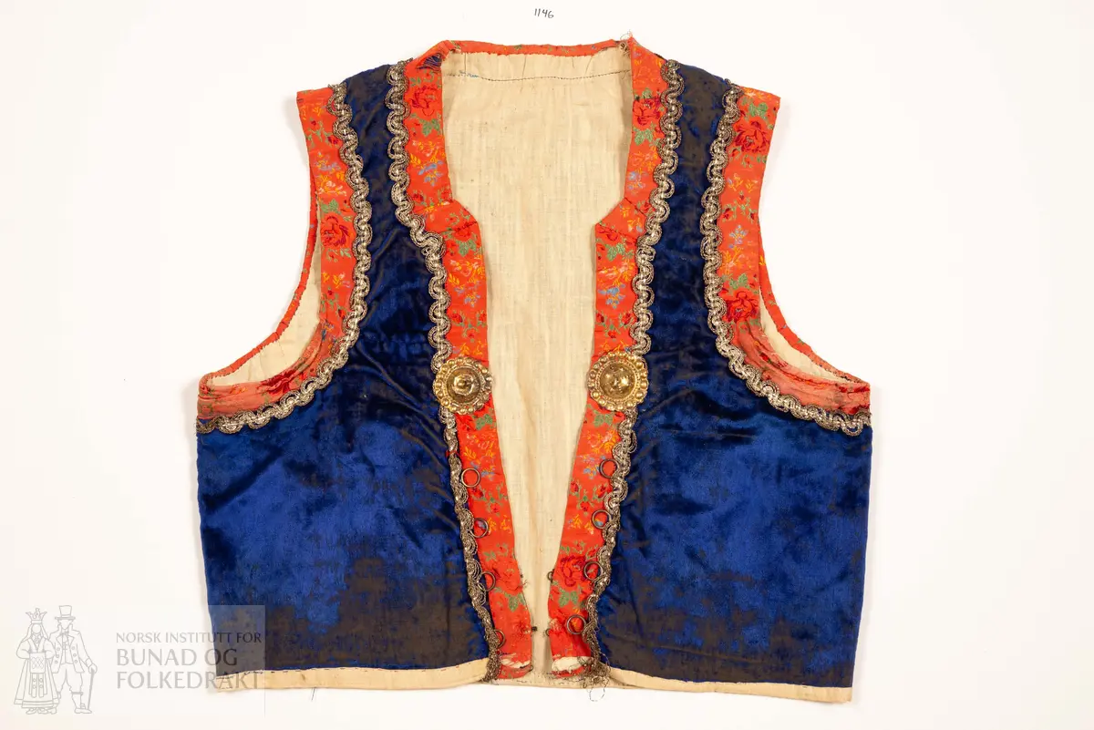 Liv, lapp med "brudeliv 1908".
Liv i blå silkeplysj/langhåra fløyel på bomullsbott kanta med 3,3 cm breie raude silkeband med blomemønstring i raudt, gult, blått og grønt. Innafor ei 1,5 cm agramanblonde.
Sidesaum og skuldersaum er bakoverflytta, rett ringing i hals bak, med snippa som peika nedover. Mjukt forma framkant som møtest i midja.
I framkant, på kvar side, fire maljer festa i stoffet mellom silkeband og agramanblonda, med belegg i bomullslerret på bakside. Første malje er 3,2 cm opp frå nedkant, siste 12,7 cm opp.
19 cm frå nedkanten på det raude silkebandet er ei stor bore (4 cm bred). Løv mangla.
På innsida ein glissen, naturfarga bomullslerret. Kanta rundt til framsida.
Vrangsydd fôr i side- og skuldersauma; maskinsauma.
Raudt band er maskinsauma i ytterkant; ellers er livet berre handsauma.
I livhøgde to små, sekundære hemper og hekter.