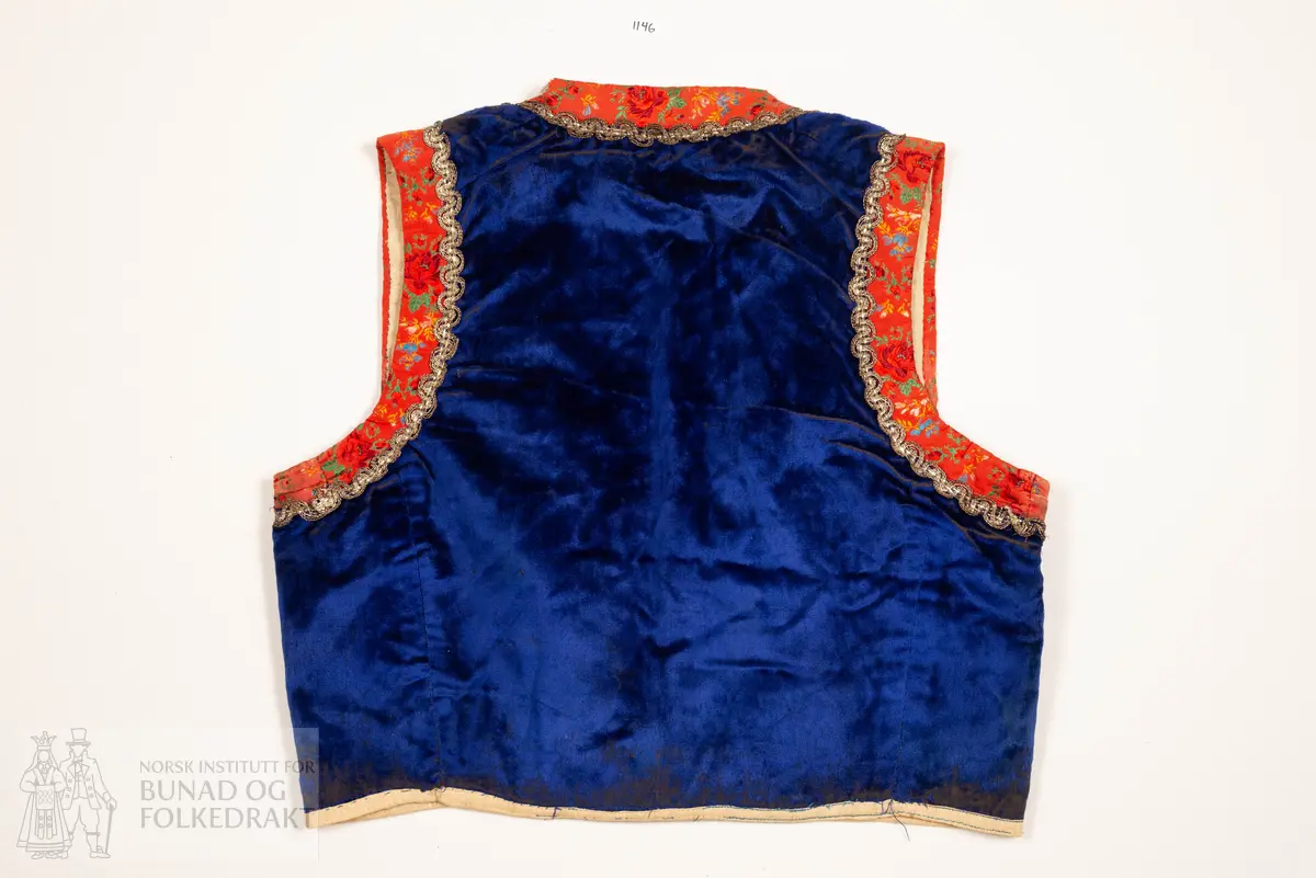 Liv, lapp med "brudeliv 1908".
Liv i blå silkeplysj/langhåra fløyel på bomullsbott kanta med 3,3 cm breie raude silkeband med blomemønstring i raudt, gult, blått og grønt. Innafor ei 1,5 cm agramanblonde.
Sidesaum og skuldersaum er bakoverflytta, rett ringing i hals bak, med snippa som peika nedover. Mjukt forma framkant som møtest i midja.
I framkant, på kvar side, fire maljer festa i stoffet mellom silkeband og agramanblonda, med belegg i bomullslerret på bakside. Første malje er 3,2 cm opp frå nedkant, siste 12,7 cm opp.
19 cm frå nedkanten på det raude silkebandet er ei stor bore (4 cm bred). Løv mangla.
På innsida ein glissen, naturfarga bomullslerret. Kanta rundt til framsida.
Vrangsydd fôr i side- og skuldersauma; maskinsauma.
Raudt band er maskinsauma i ytterkant; ellers er livet berre handsauma.
I livhøgde to små, sekundære hemper og hekter.