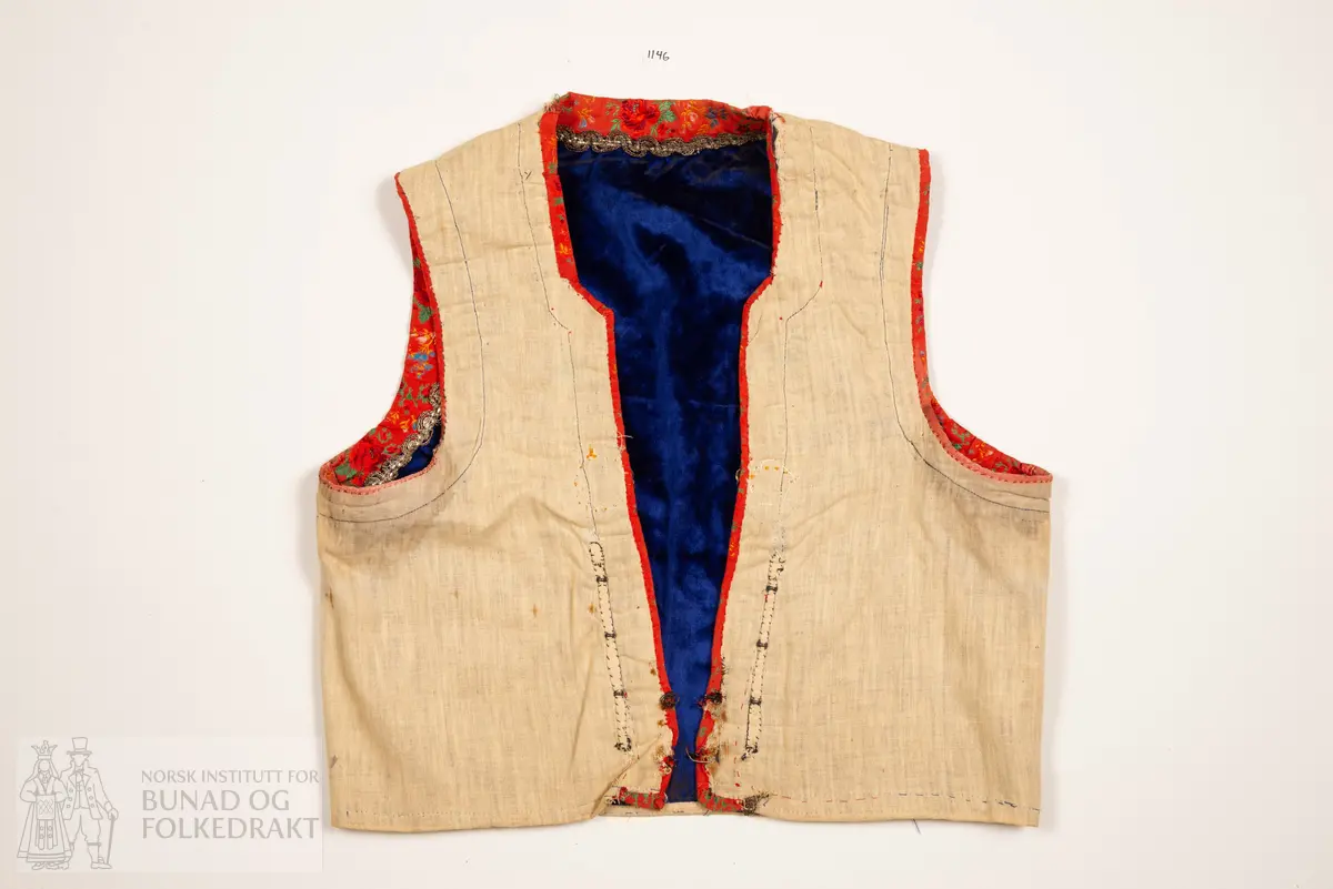 Liv, lapp med "brudeliv 1908".
Liv i blå silkeplysj/langhåra fløyel på bomullsbott kanta med 3,3 cm breie raude silkeband med blomemønstring i raudt, gult, blått og grønt. Innafor ei 1,5 cm agramanblonde.
Sidesaum og skuldersaum er bakoverflytta, rett ringing i hals bak, med snippa som peika nedover. Mjukt forma framkant som møtest i midja.
I framkant, på kvar side, fire maljer festa i stoffet mellom silkeband og agramanblonda, med belegg i bomullslerret på bakside. Første malje er 3,2 cm opp frå nedkant, siste 12,7 cm opp.
19 cm frå nedkanten på det raude silkebandet er ei stor bore (4 cm bred). Løv mangla.
På innsida ein glissen, naturfarga bomullslerret. Kanta rundt til framsida.
Vrangsydd fôr i side- og skuldersauma; maskinsauma.
Raudt band er maskinsauma i ytterkant; ellers er livet berre handsauma.
I livhøgde to små, sekundære hemper og hekter.