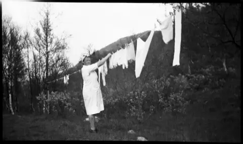 Kvinne henger opp klesvask på uteområdet på Krokan.