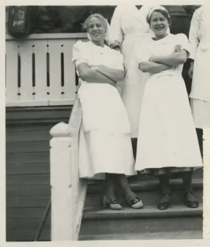 Kvinner i uniform stående i trappa på baksiden av Krokan hotell.