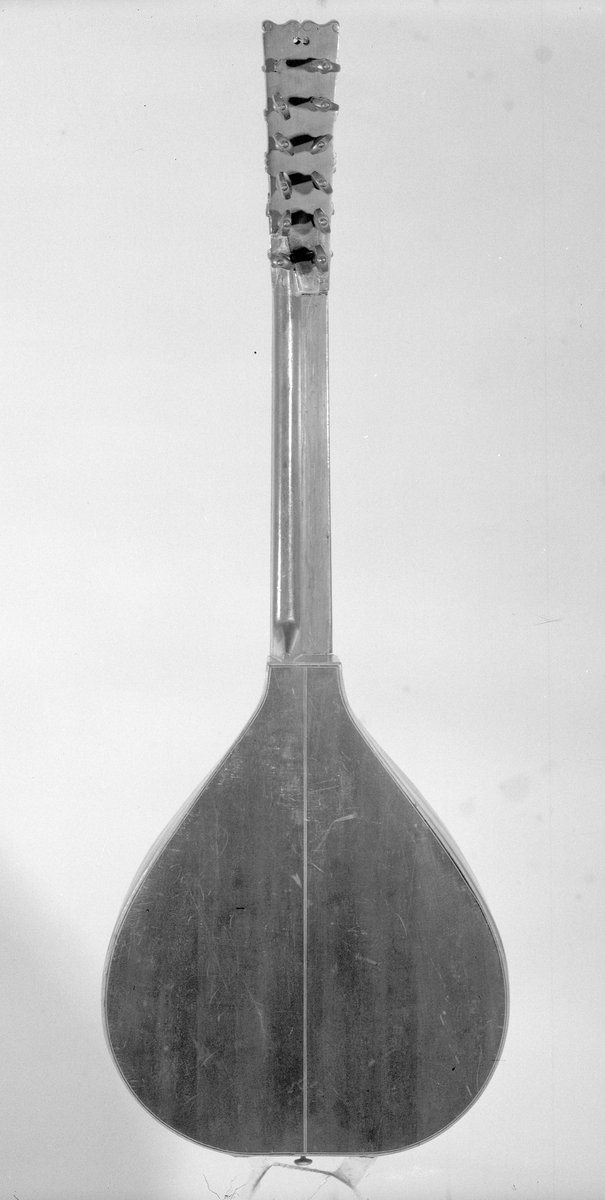 Cister med päronformad hals och ett runt resonanshål. Lång hals. Tolv stämskruvar i ett huvud som är platt. Inte som på en fiol. 