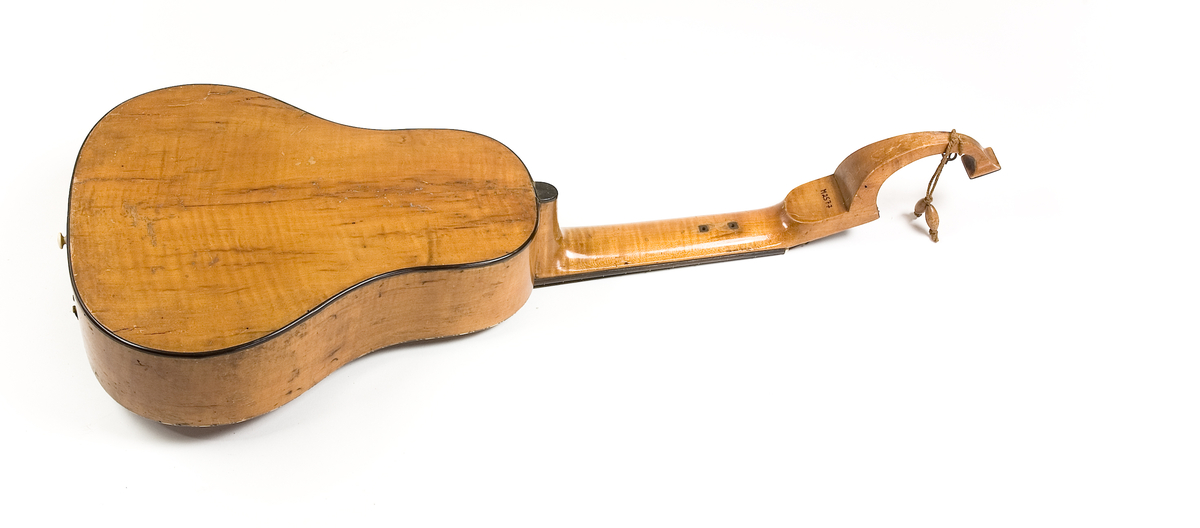 Klockformad English guitar(Cister) med stämmekanik av engelsk Prestontyp. Rosetten har ett tvärgående långt hål där hammare syns som slagit mot strängen underifrån. På lockets ena sida rester av en tangenmekanism med 7 tangenter. 