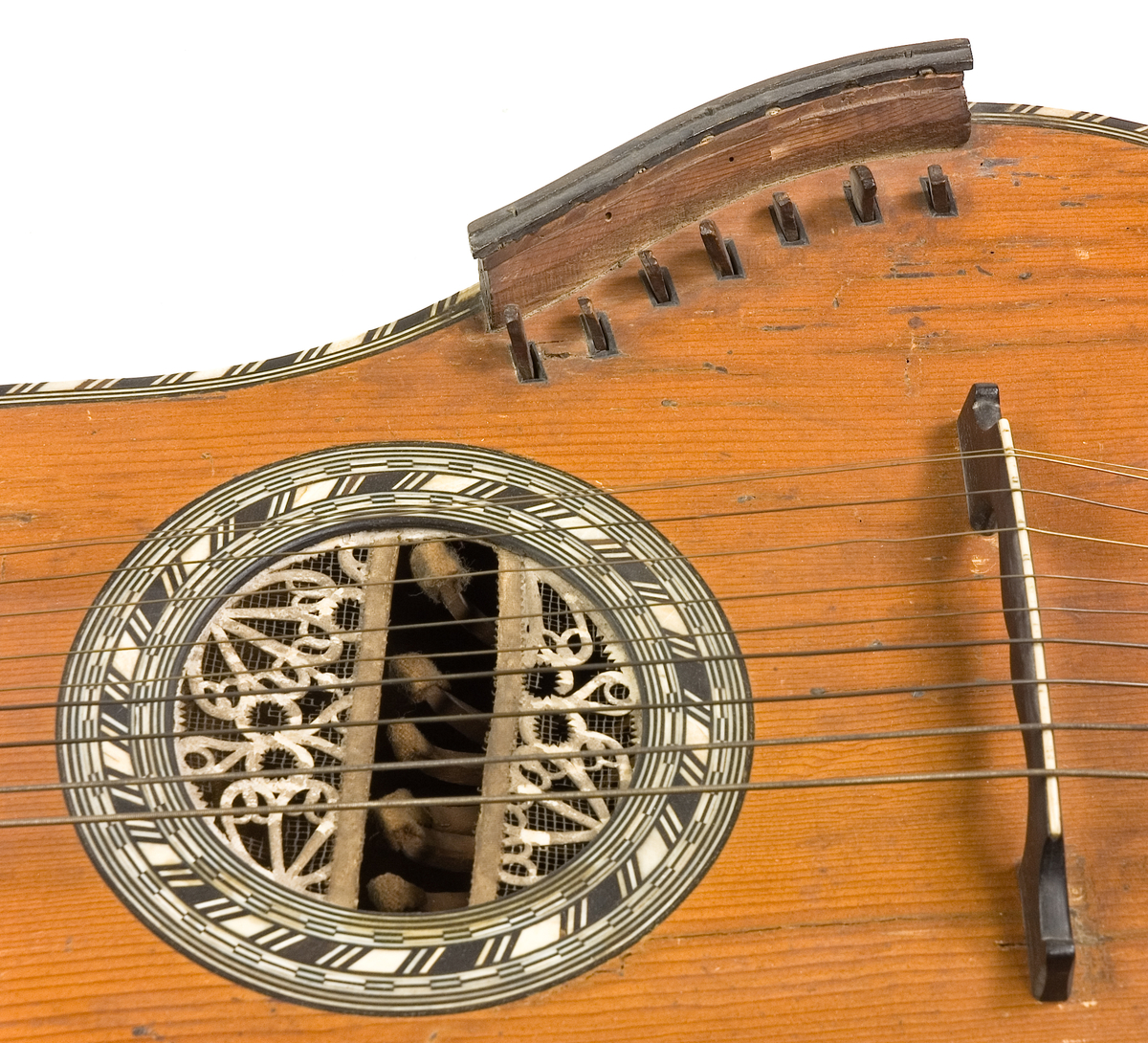 Klockformad English guitar(Cister) med stämmekanik av engelsk Prestontyp. Rosetten har ett tvärgående långt hål där hammare syns som slagit mot strängen underifrån. På lockets ena sida rester av en tangenmekanism med 7 tangenter. 