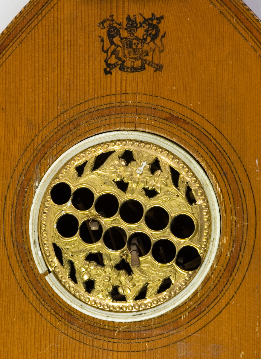 Cister av engelsk modell (English guitar) med tangentfunktion. Oval korpus med en lucka i sargen för att nå tangentmekaniken. 6 tangenter på locket. Resonanshål med rosett av mässing. På locket nedanför greppbrädan en stämpel med tillverkarens namn. Stämmekanik av Prestonmodell som stäms med urmakarnyckel. 