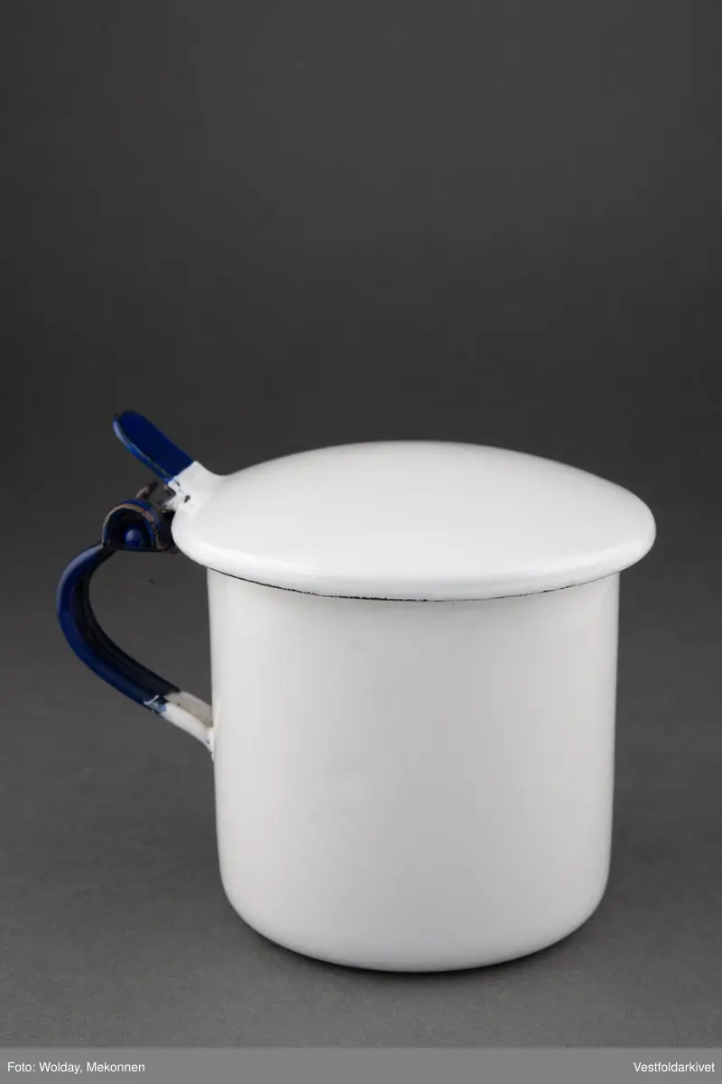 Krukke med lokk, hvit med blå hank. Lokket er hengslet.
Laget av emaljert metall.