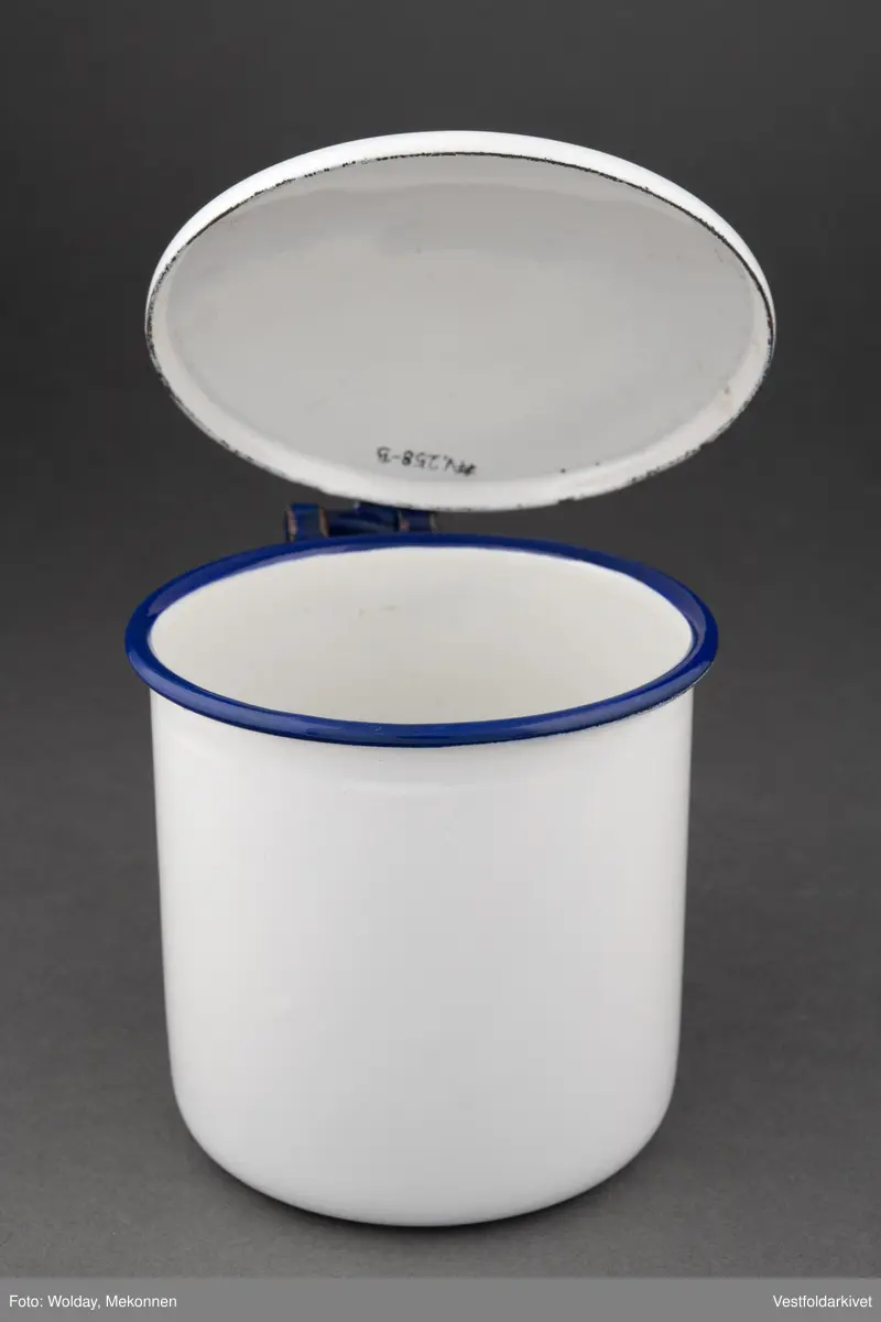 Krukke med lokk, hvit med blå hank. Lokket er hengslet.
Laget av emaljert metall.