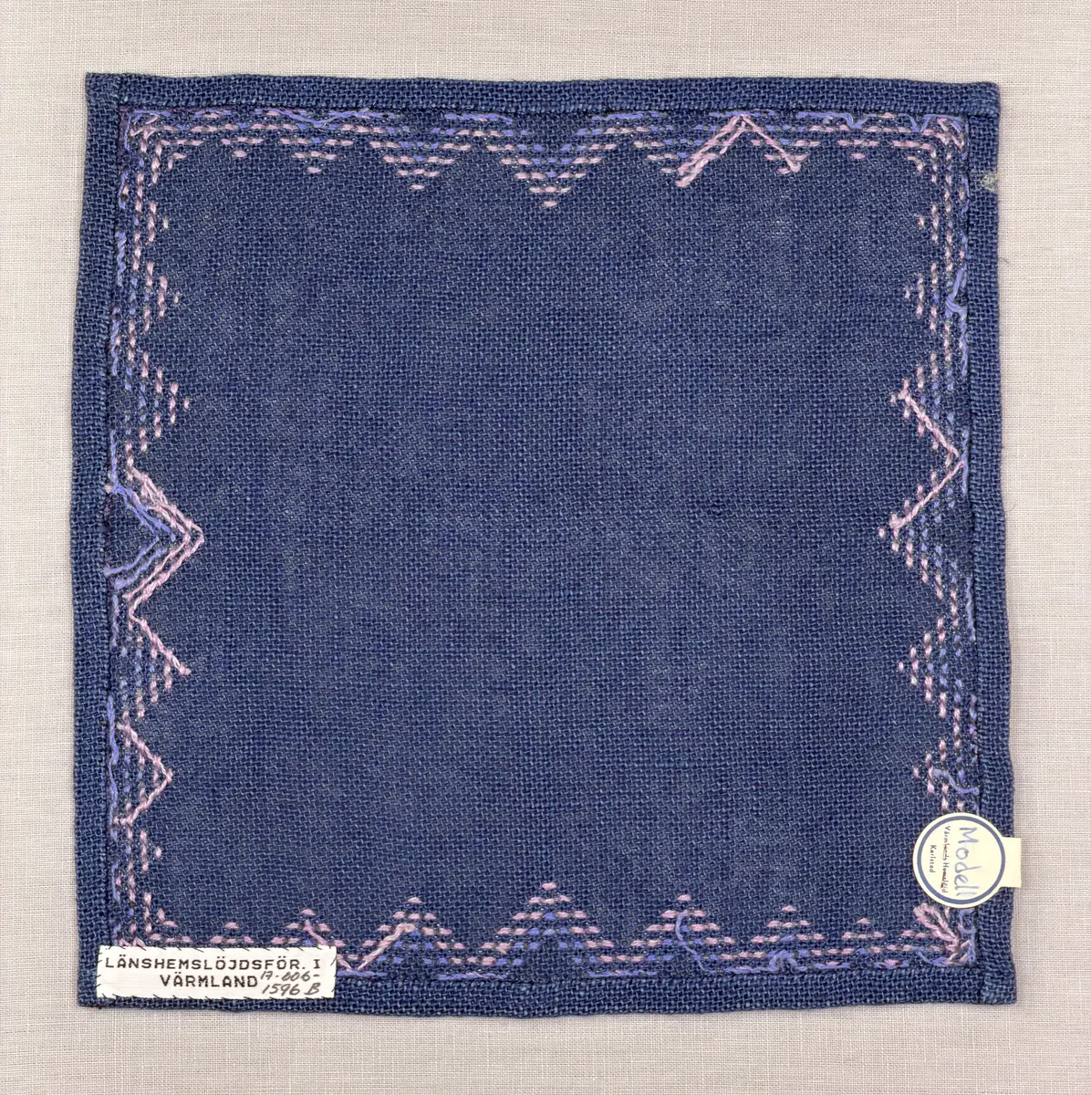 Bordsduk gjord av linneväv med 7,5tr/cm i tuskaft och broderi utfört med lintråd i edasöm och halva korsstygn sydda över tre trådar. Duken har 9mm bred dubbelvikt fåll runt om och raka hörn sömmade med kaststygn.
