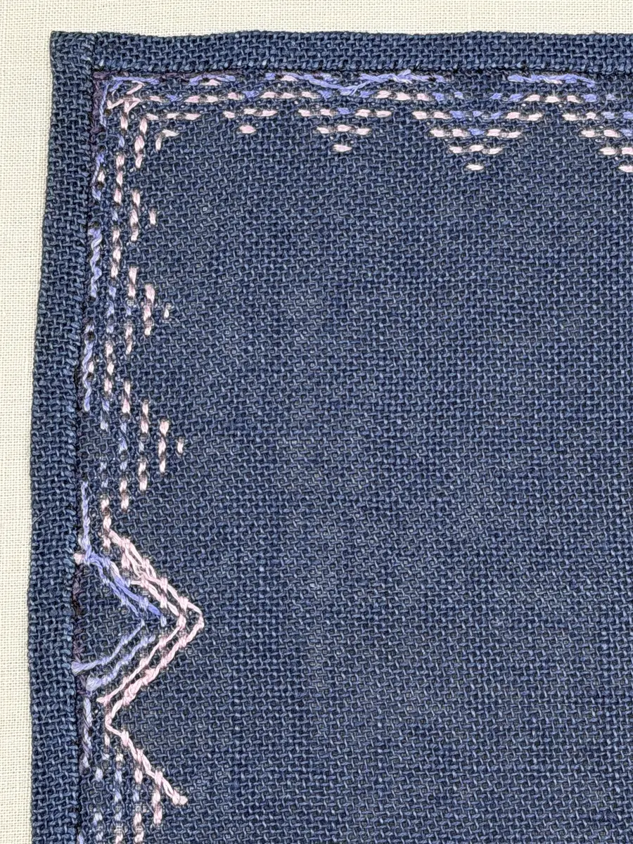 Bordsduk gjord av linneväv med 7,5tr/cm i tuskaft och broderi utfört med lintråd i edasöm och halva korsstygn sydda över tre trådar. Duken har 9mm bred dubbelvikt fåll runt om och raka hörn sömmade med kaststygn.
