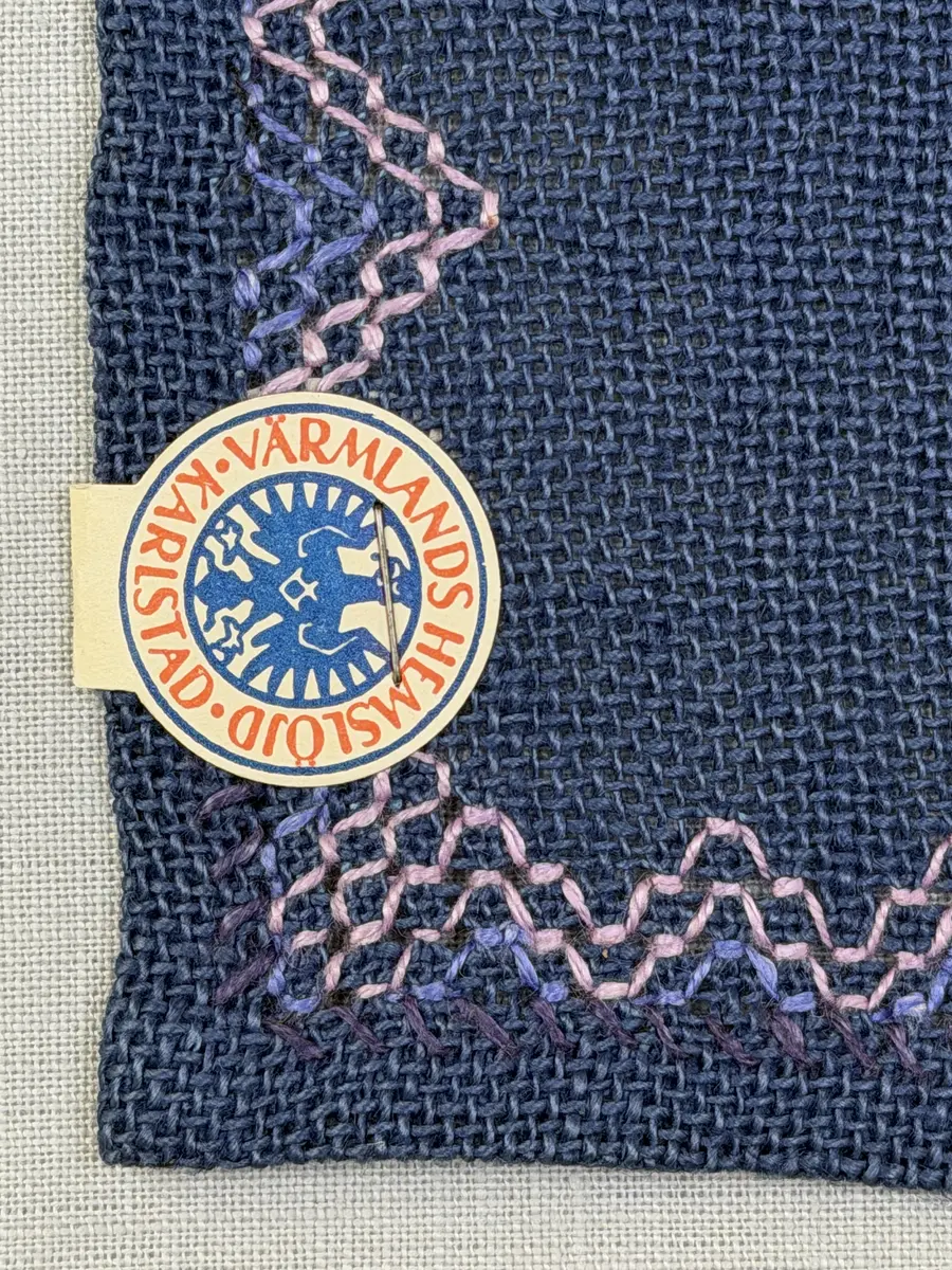 Bordsduk gjord av linneväv med 7,5tr/cm i tuskaft och broderi utfört med lintråd i edasöm och halva korsstygn sydda över tre trådar. Duken har 9mm bred dubbelvikt fåll runt om och raka hörn sömmade med kaststygn.
