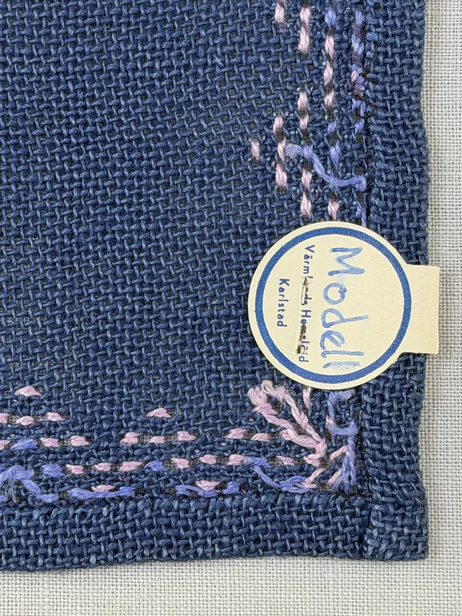 Bordsduk gjord av linneväv med 7,5tr/cm i tuskaft och broderi utfört med lintråd i edasöm och halva korsstygn sydda över tre trådar. Duken har 9mm bred dubbelvikt fåll runt om och raka hörn sömmade med kaststygn.
