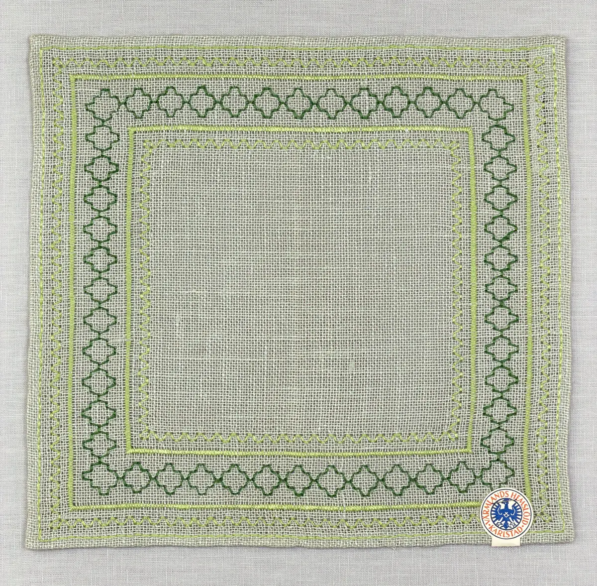 Bordsduk gjord av linneväv med 8tr/cm i tuskaft och broderi utfört med lintråd i åtdragen kastsöm och edasöm sydd över tre trådar. Duken har 7mm bred dubbelvikt fåll runt om fastsydd med dubbla förstygn samt raka hörn, vilka är sömmade med kaststygn.
