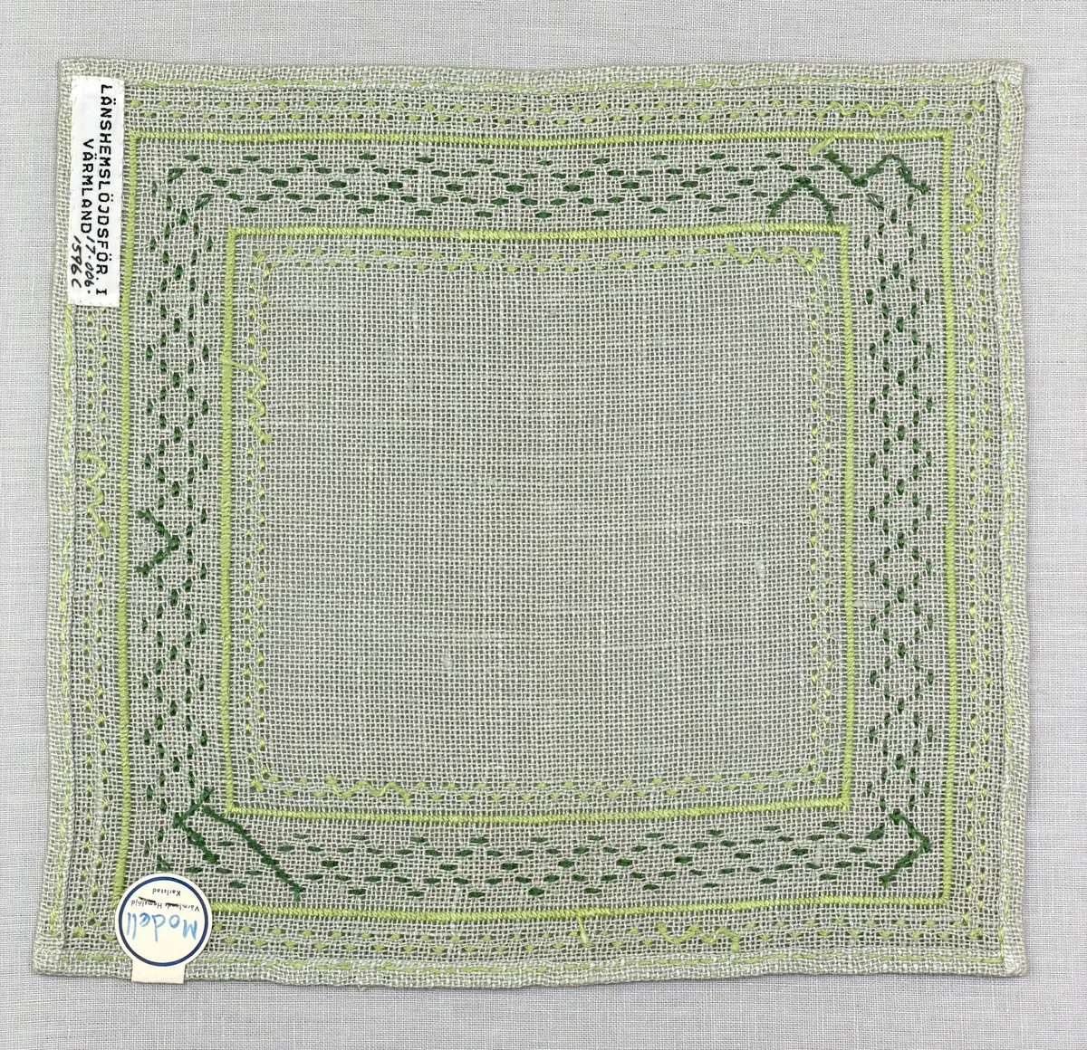 Bordsduk gjord av linneväv med 8tr/cm i tuskaft och broderi utfört med lintråd i åtdragen kastsöm och edasöm sydd över tre trådar. Duken har 7mm bred dubbelvikt fåll runt om fastsydd med dubbla förstygn samt raka hörn, vilka är sömmade med kaststygn.
