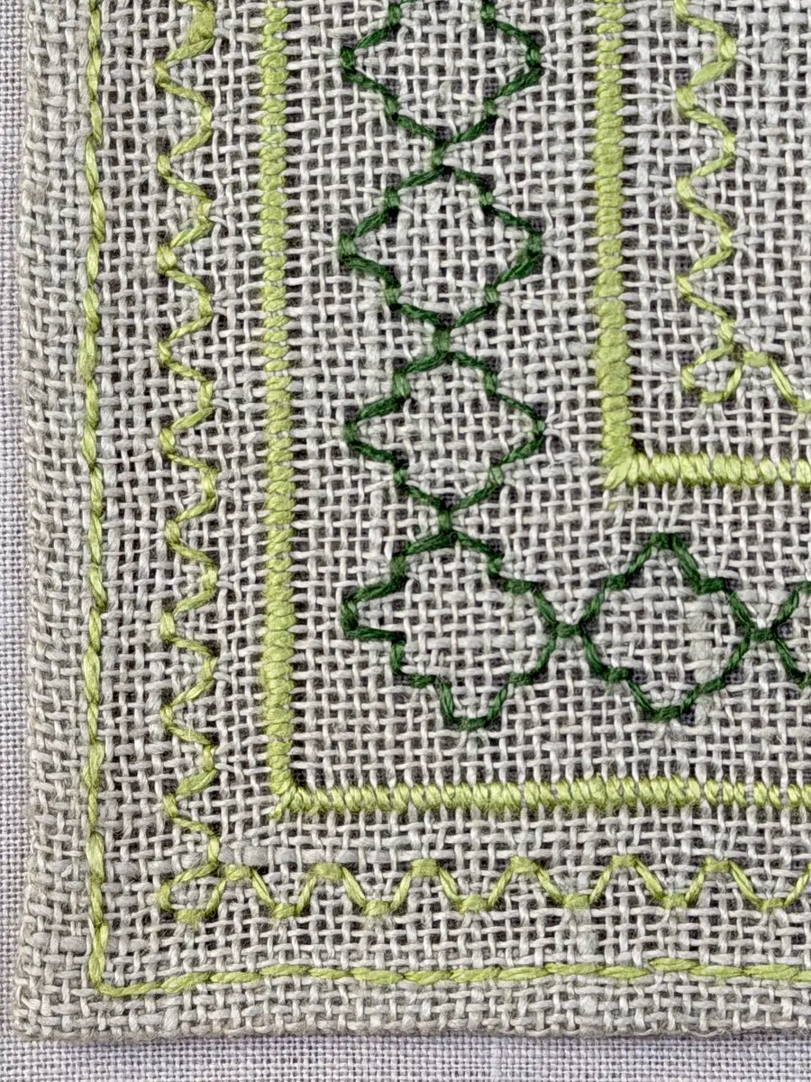 Bordsduk gjord av linneväv med 8tr/cm i tuskaft och broderi utfört med lintråd i åtdragen kastsöm och edasöm sydd över tre trådar. Duken har 7mm bred dubbelvikt fåll runt om fastsydd med dubbla förstygn samt raka hörn, vilka är sömmade med kaststygn.
