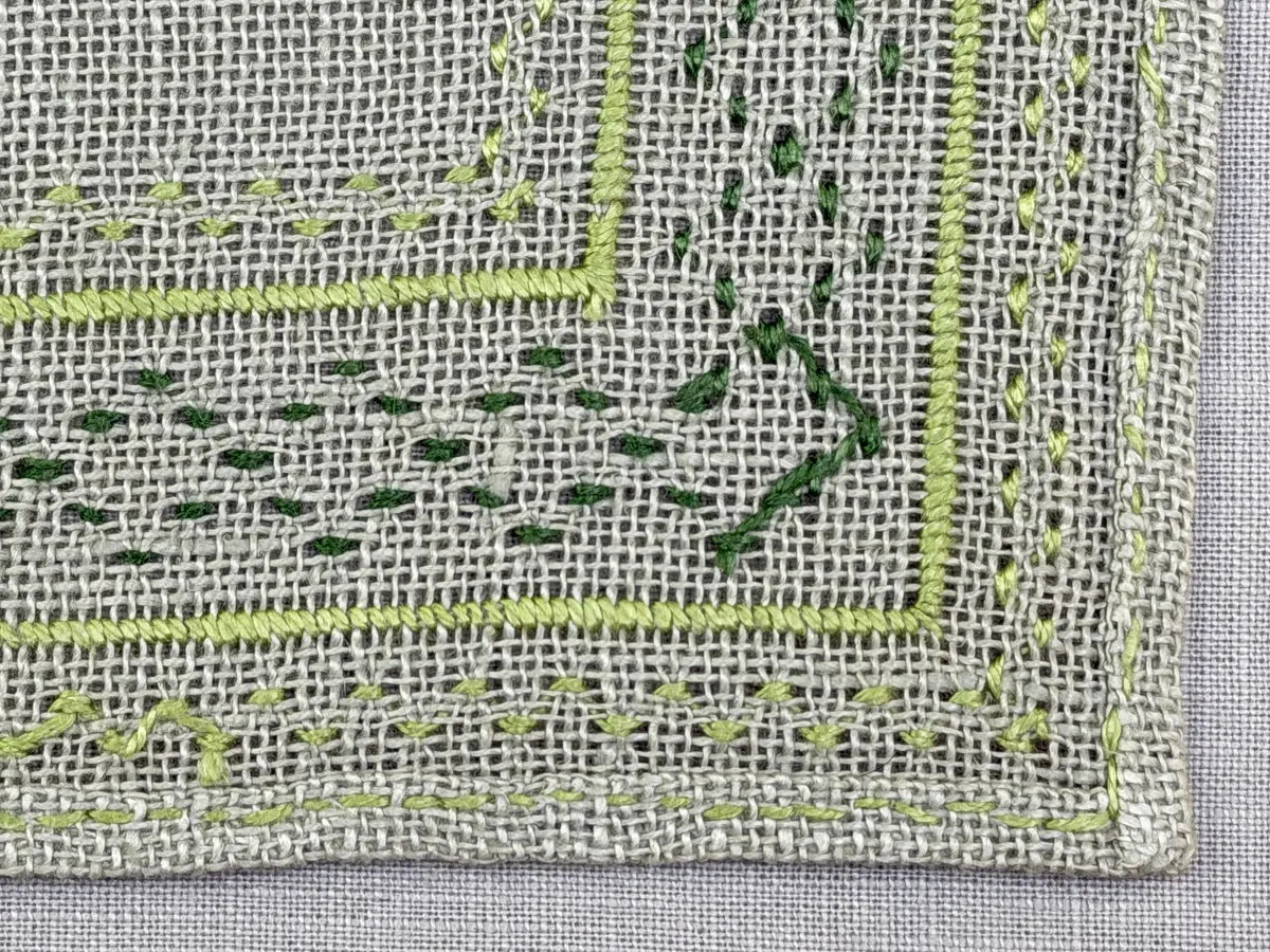 Bordsduk gjord av linneväv med 8tr/cm i tuskaft och broderi utfört med lintråd i åtdragen kastsöm och edasöm sydd över tre trådar. Duken har 7mm bred dubbelvikt fåll runt om fastsydd med dubbla förstygn samt raka hörn, vilka är sömmade med kaststygn.
