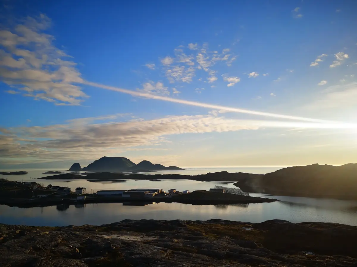 Oversiktsbilde av Gjesvær tatt fra en høyde. Himmel, hav og berg.