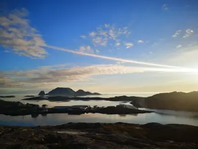 Oversiktsbilde av Gjesvær tatt fra en høyde. Himmel, hav og berg.