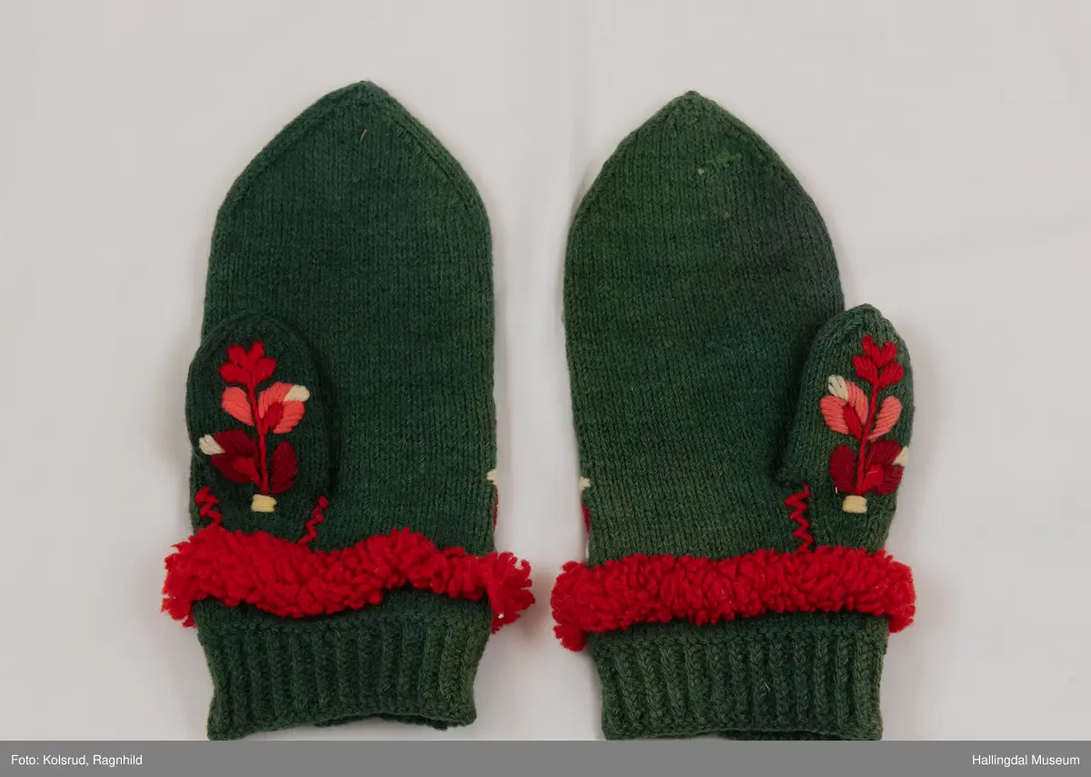 Votter i glattstrikking. Ullbroderi, stilisert rosemotiv i fargane kvitt, gult, oransje, rosa, raudt, fiolett og blått. Det er hallingsaum. Mellom broderi og vrangbord ei raud bord med tette trafs (frynser). Lite motiv i kvitt, gult, rosa og raudt på tommelen.