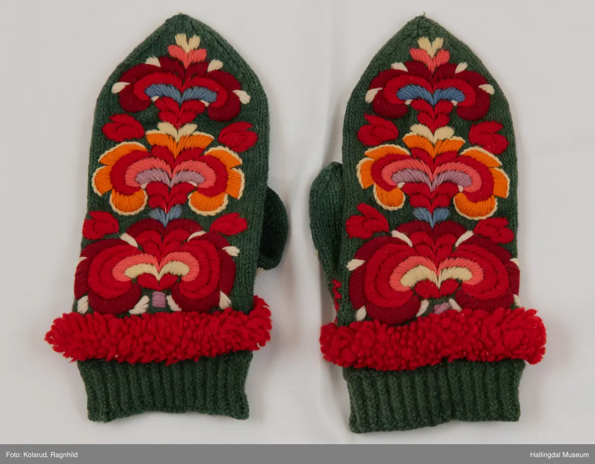 Votter i glattstrikking. Ullbroderi, stilisert rosemotiv i fargane kvitt, gult, oransje, rosa, raudt, fiolett og blått. Det er hallingsaum. Mellom broderi og vrangbord ei raud bord med tette trafs (frynser). Lite motiv i kvitt, gult, rosa og raudt på tommelen.