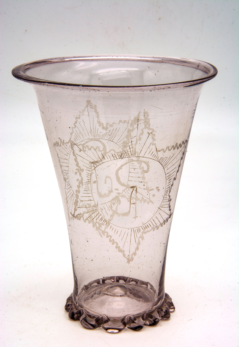 Glas med etsningar. Glaset är märkt "CA."