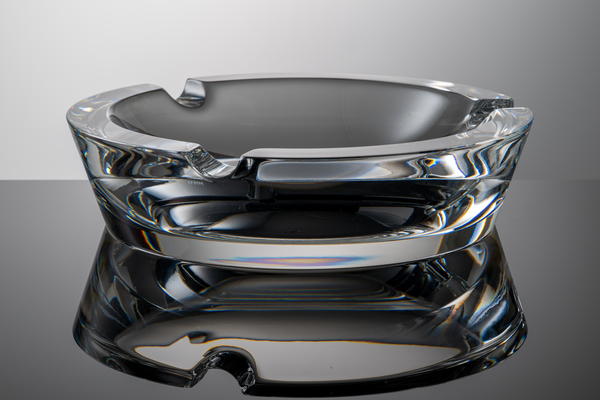 Formgivare: Lars Hellsten. Askfat i klarglas, rund form med tre urtag i mynningskanten.