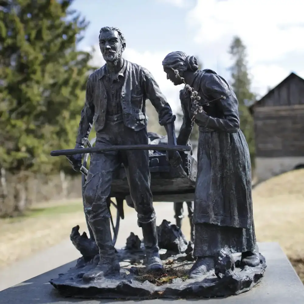 Skulptur i friluftsmuseum, viser en familie som trekker en håndkjerre etter seg. 