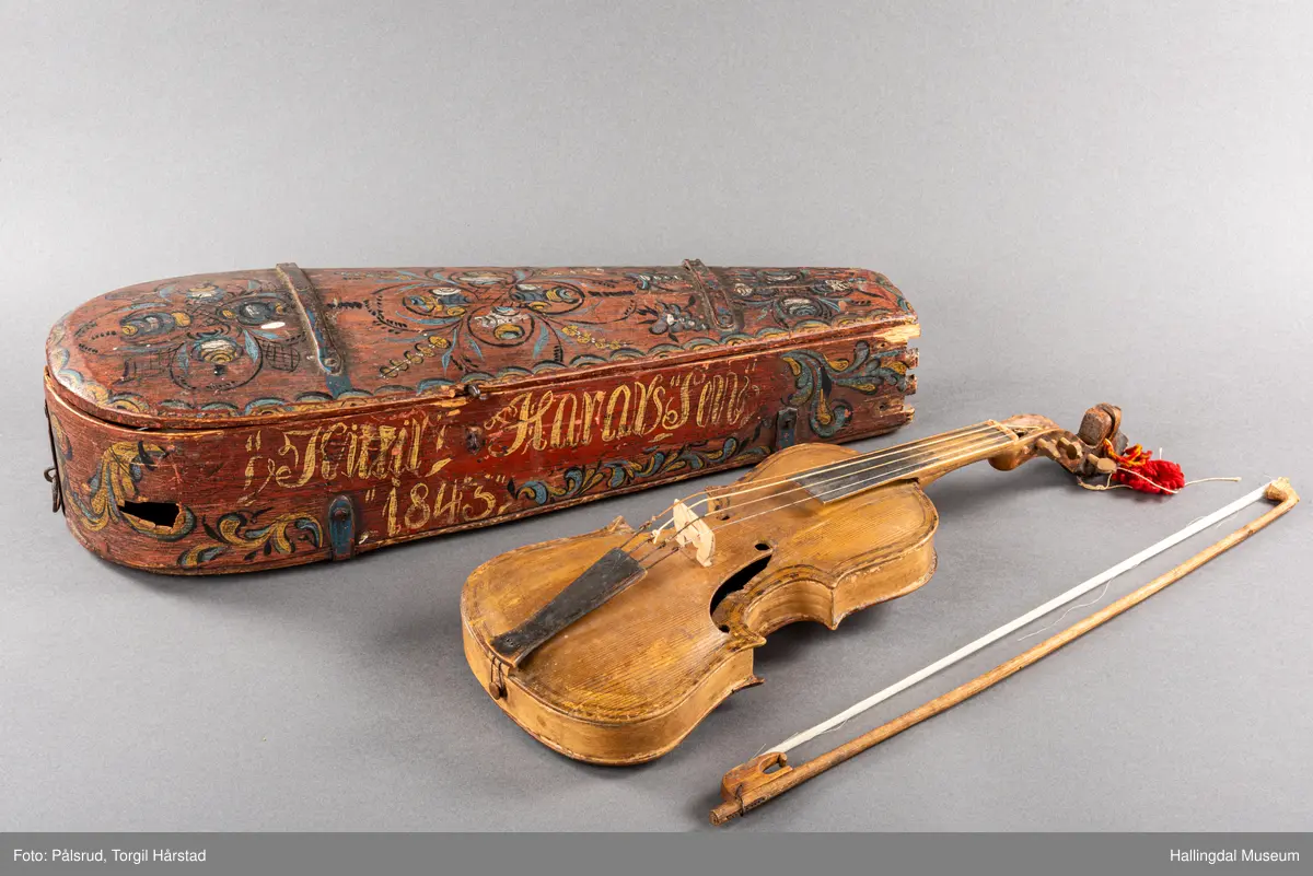 a) fele, b) bue, c) felekasse.  Bjerk, meget defekt resonanskasse.  Oversiden brukket i 3 løse deler.  Et stort stykke mangler.  Resonansbunnen lakkert, har malte profiler.  Har bare tre strenger.  Mangler flere nøkler.  Halsen avsluttes med utskåret løvehode.  Rød og gul ullsnor med dusk bundet fast til løvehodet.  Fingerbrettet har ingen gradering.  
b) Buen en rund pinne av gran.  I den ene enden skåret i L-form.  Feste for buestreng.  Strengen defekt.  I den andre enden er en takket jernbit festet i en snor.   Utsåret bjerkekloss festet i jerntråd.  
c) Gran, skåret.  Selve kassen består av et bredt bord, bøyd til hesteskoform og avsluttet med fire fjær til sinking i hver ende.  Sluttstykke mangler.  Bunnen laget av ett bord.  Festet til veggen med fire jernbeslag utvendig og en lærbit som erstatter et beslag.  Dette pluss ett av de andre beslagene går tvers over veggen og danner hengsler for lokket som er laget av ett bord, svakt hvelvet.   Liten k jernkrampe i lokk-kanten.  Tilsvarende i veggen.  Beslaget  på toppen av "hesteskoen" har en liten jernkrampe med jernring.  Lokk og vegger er overmalt.  Bunnfarge brun.  Veggen akantus i gult, sort , blått og hvitt.  Beslagene blåmalt.  På samme side som jernkrampe bokstaver og tall malt med gult:  KITTIL HARALSSEN 1843.  Veggen har to store hull.  Lokket har blomsterdekor i samme farge som veggene.  Innvendig brunmalt.  Stort stykke spikket bort.  18/8-64. Å Astrup

Fela er nå restaurert og satt i full stand. 5/3-1979, K.K.Nøklebye