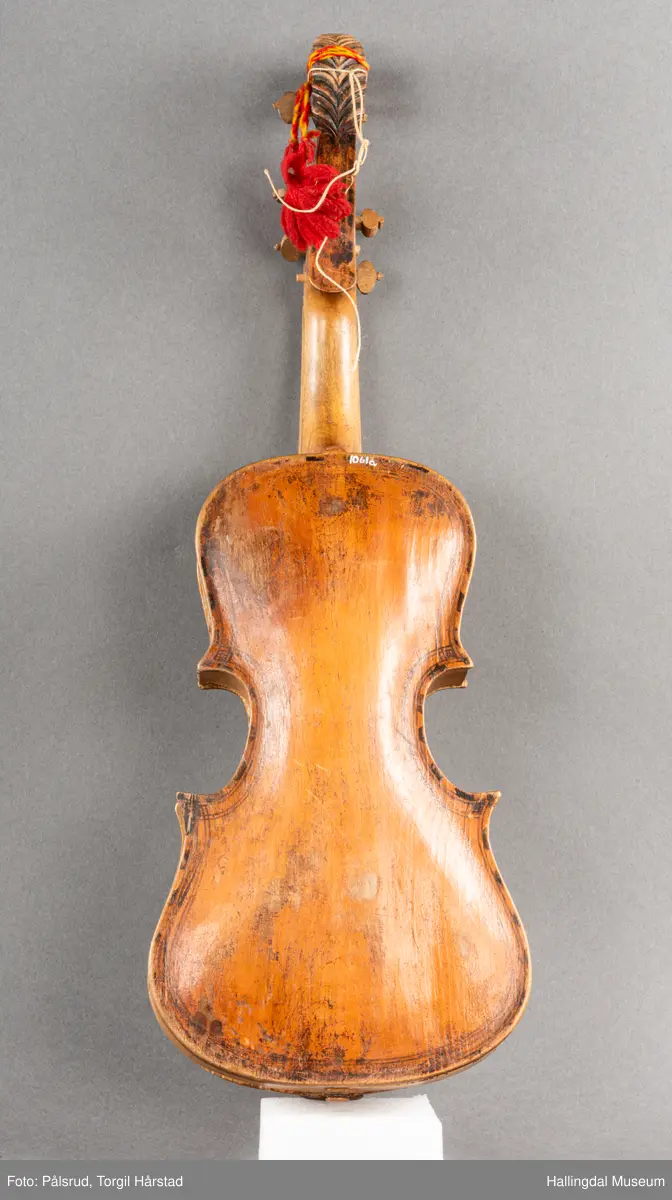 a) fele, b) bue, c) felekasse.  Bjerk, meget defekt resonanskasse.  Oversiden brukket i 3 løse deler.  Et stort stykke mangler.  Resonansbunnen lakkert, har malte profiler.  Har bare tre strenger.  Mangler flere nøkler.  Halsen avsluttes med utskåret løvehode.  Rød og gul ullsnor med dusk bundet fast til løvehodet.  Fingerbrettet har ingen gradering.  
b) Buen en rund pinne av gran.  I den ene enden skåret i L-form.  Feste for buestreng.  Strengen defekt.  I den andre enden er en takket jernbit festet i en snor.   Utsåret bjerkekloss festet i jerntråd.  
c) Gran, skåret.  Selve kassen består av et bredt bord, bøyd til hesteskoform og avsluttet med fire fjær til sinking i hver ende.  Sluttstykke mangler.  Bunnen laget av ett bord.  Festet til veggen med fire jernbeslag utvendig og en lærbit som erstatter et beslag.  Dette pluss ett av de andre beslagene går tvers over veggen og danner hengsler for lokket som er laget av ett bord, svakt hvelvet.   Liten k jernkrampe i lokk-kanten.  Tilsvarende i veggen.  Beslaget  på toppen av "hesteskoen" har en liten jernkrampe med jernring.  Lokk og vegger er overmalt.  Bunnfarge brun.  Veggen akantus i gult, sort , blått og hvitt.  Beslagene blåmalt.  På samme side som jernkrampe bokstaver og tall malt med gult:  KITTIL HARALSSEN 1843.  Veggen har to store hull.  Lokket har blomsterdekor i samme farge som veggene.  Innvendig brunmalt.  Stort stykke spikket bort.  18/8-64. Å Astrup

Fela er nå restaurert og satt i full stand. 5/3-1979, K.K.Nøklebye