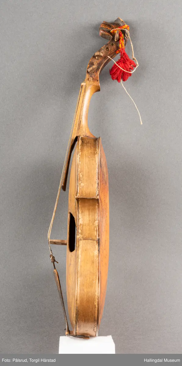 a) fele, b) bue, c) felekasse.  Bjerk, meget defekt resonanskasse.  Oversiden brukket i 3 løse deler.  Et stort stykke mangler.  Resonansbunnen lakkert, har malte profiler.  Har bare tre strenger.  Mangler flere nøkler.  Halsen avsluttes med utskåret løvehode.  Rød og gul ullsnor med dusk bundet fast til løvehodet.  Fingerbrettet har ingen gradering.  
b) Buen en rund pinne av gran.  I den ene enden skåret i L-form.  Feste for buestreng.  Strengen defekt.  I den andre enden er en takket jernbit festet i en snor.   Utsåret bjerkekloss festet i jerntråd.  
c) Gran, skåret.  Selve kassen består av et bredt bord, bøyd til hesteskoform og avsluttet med fire fjær til sinking i hver ende.  Sluttstykke mangler.  Bunnen laget av ett bord.  Festet til veggen med fire jernbeslag utvendig og en lærbit som erstatter et beslag.  Dette pluss ett av de andre beslagene går tvers over veggen og danner hengsler for lokket som er laget av ett bord, svakt hvelvet.   Liten k jernkrampe i lokk-kanten.  Tilsvarende i veggen.  Beslaget  på toppen av "hesteskoen" har en liten jernkrampe med jernring.  Lokk og vegger er overmalt.  Bunnfarge brun.  Veggen akantus i gult, sort , blått og hvitt.  Beslagene blåmalt.  På samme side som jernkrampe bokstaver og tall malt med gult:  KITTIL HARALSSEN 1843.  Veggen har to store hull.  Lokket har blomsterdekor i samme farge som veggene.  Innvendig brunmalt.  Stort stykke spikket bort.  18/8-64. Å Astrup

Fela er nå restaurert og satt i full stand. 5/3-1979, K.K.Nøklebye