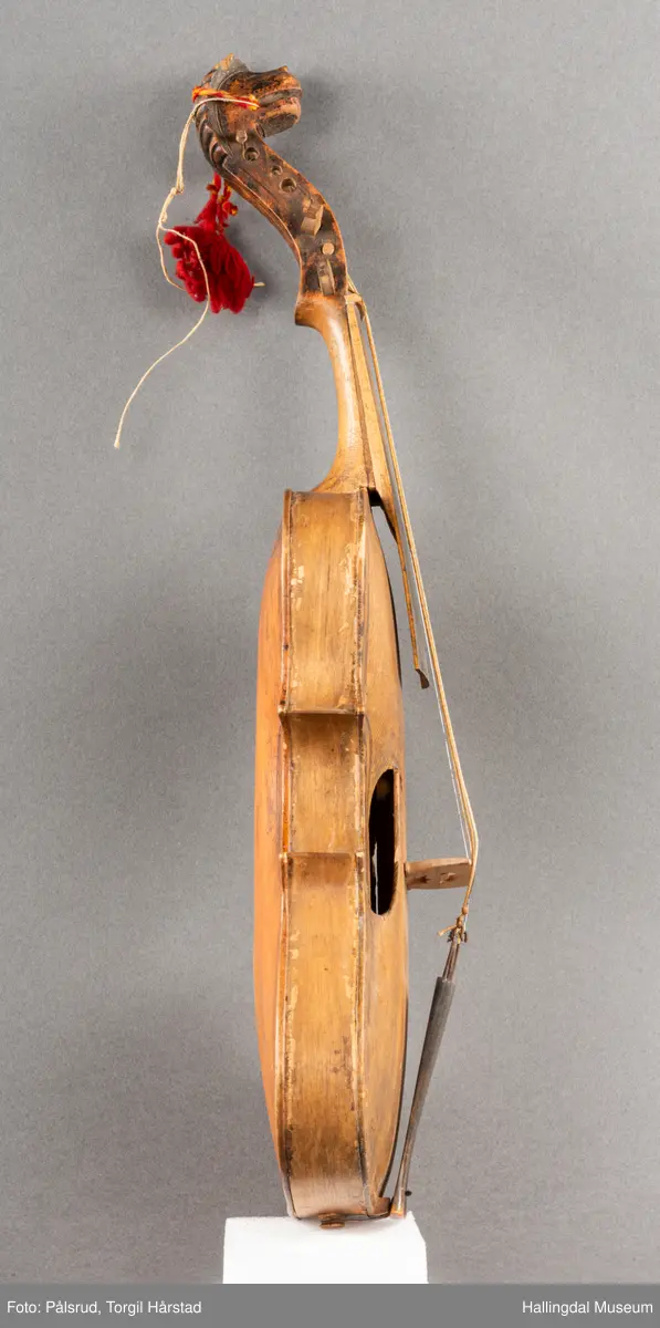 a) fele, b) bue, c) felekasse.  Bjerk, meget defekt resonanskasse.  Oversiden brukket i 3 løse deler.  Et stort stykke mangler.  Resonansbunnen lakkert, har malte profiler.  Har bare tre strenger.  Mangler flere nøkler.  Halsen avsluttes med utskåret løvehode.  Rød og gul ullsnor med dusk bundet fast til løvehodet.  Fingerbrettet har ingen gradering.  
b) Buen en rund pinne av gran.  I den ene enden skåret i L-form.  Feste for buestreng.  Strengen defekt.  I den andre enden er en takket jernbit festet i en snor.   Utsåret bjerkekloss festet i jerntråd.  
c) Gran, skåret.  Selve kassen består av et bredt bord, bøyd til hesteskoform og avsluttet med fire fjær til sinking i hver ende.  Sluttstykke mangler.  Bunnen laget av ett bord.  Festet til veggen med fire jernbeslag utvendig og en lærbit som erstatter et beslag.  Dette pluss ett av de andre beslagene går tvers over veggen og danner hengsler for lokket som er laget av ett bord, svakt hvelvet.   Liten k jernkrampe i lokk-kanten.  Tilsvarende i veggen.  Beslaget  på toppen av "hesteskoen" har en liten jernkrampe med jernring.  Lokk og vegger er overmalt.  Bunnfarge brun.  Veggen akantus i gult, sort , blått og hvitt.  Beslagene blåmalt.  På samme side som jernkrampe bokstaver og tall malt med gult:  KITTIL HARALSSEN 1843.  Veggen har to store hull.  Lokket har blomsterdekor i samme farge som veggene.  Innvendig brunmalt.  Stort stykke spikket bort.  18/8-64. Å Astrup

Fela er nå restaurert og satt i full stand. 5/3-1979, K.K.Nøklebye