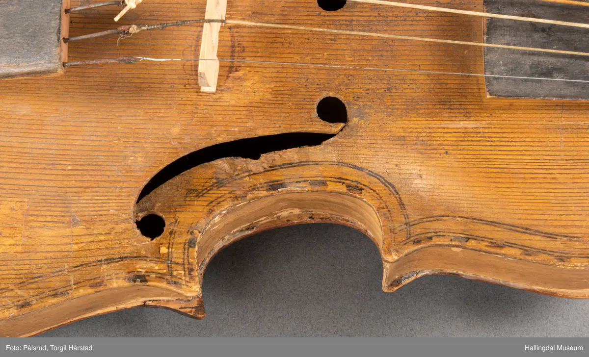 a) fele, b) bue, c) felekasse.  Bjerk, meget defekt resonanskasse.  Oversiden brukket i 3 løse deler.  Et stort stykke mangler.  Resonansbunnen lakkert, har malte profiler.  Har bare tre strenger.  Mangler flere nøkler.  Halsen avsluttes med utskåret løvehode.  Rød og gul ullsnor med dusk bundet fast til løvehodet.  Fingerbrettet har ingen gradering.  
b) Buen en rund pinne av gran.  I den ene enden skåret i L-form.  Feste for buestreng.  Strengen defekt.  I den andre enden er en takket jernbit festet i en snor.   Utsåret bjerkekloss festet i jerntråd.  
c) Gran, skåret.  Selve kassen består av et bredt bord, bøyd til hesteskoform og avsluttet med fire fjær til sinking i hver ende.  Sluttstykke mangler.  Bunnen laget av ett bord.  Festet til veggen med fire jernbeslag utvendig og en lærbit som erstatter et beslag.  Dette pluss ett av de andre beslagene går tvers over veggen og danner hengsler for lokket som er laget av ett bord, svakt hvelvet.   Liten k jernkrampe i lokk-kanten.  Tilsvarende i veggen.  Beslaget  på toppen av "hesteskoen" har en liten jernkrampe med jernring.  Lokk og vegger er overmalt.  Bunnfarge brun.  Veggen akantus i gult, sort , blått og hvitt.  Beslagene blåmalt.  På samme side som jernkrampe bokstaver og tall malt med gult:  KITTIL HARALSSEN 1843.  Veggen har to store hull.  Lokket har blomsterdekor i samme farge som veggene.  Innvendig brunmalt.  Stort stykke spikket bort.  18/8-64. Å Astrup

Fela er nå restaurert og satt i full stand. 5/3-1979, K.K.Nøklebye