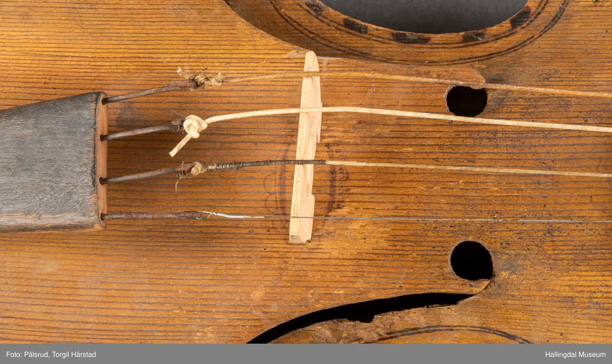 a) fele, b) bue, c) felekasse.  Bjerk, meget defekt resonanskasse.  Oversiden brukket i 3 løse deler.  Et stort stykke mangler.  Resonansbunnen lakkert, har malte profiler.  Har bare tre strenger.  Mangler flere nøkler.  Halsen avsluttes med utskåret løvehode.  Rød og gul ullsnor med dusk bundet fast til løvehodet.  Fingerbrettet har ingen gradering.  
b) Buen en rund pinne av gran.  I den ene enden skåret i L-form.  Feste for buestreng.  Strengen defekt.  I den andre enden er en takket jernbit festet i en snor.   Utsåret bjerkekloss festet i jerntråd.  
c) Gran, skåret.  Selve kassen består av et bredt bord, bøyd til hesteskoform og avsluttet med fire fjær til sinking i hver ende.  Sluttstykke mangler.  Bunnen laget av ett bord.  Festet til veggen med fire jernbeslag utvendig og en lærbit som erstatter et beslag.  Dette pluss ett av de andre beslagene går tvers over veggen og danner hengsler for lokket som er laget av ett bord, svakt hvelvet.   Liten k jernkrampe i lokk-kanten.  Tilsvarende i veggen.  Beslaget  på toppen av "hesteskoen" har en liten jernkrampe med jernring.  Lokk og vegger er overmalt.  Bunnfarge brun.  Veggen akantus i gult, sort , blått og hvitt.  Beslagene blåmalt.  På samme side som jernkrampe bokstaver og tall malt med gult:  KITTIL HARALSSEN 1843.  Veggen har to store hull.  Lokket har blomsterdekor i samme farge som veggene.  Innvendig brunmalt.  Stort stykke spikket bort.  18/8-64. Å Astrup

Fela er nå restaurert og satt i full stand. 5/3-1979, K.K.Nøklebye